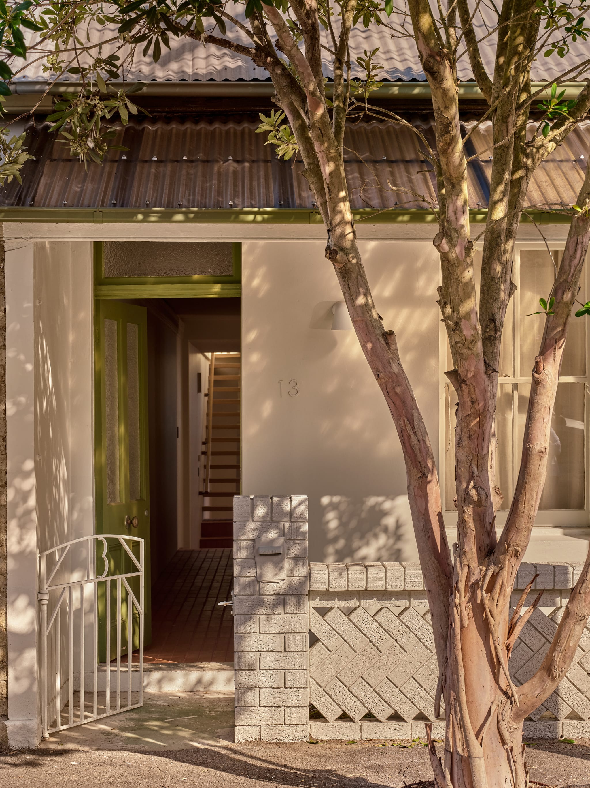 Birchgrove heritage terrace facade with corrugated iron awning, an olive-green door and painted brick fence, a crepe myrtle shading the entry marked 13.